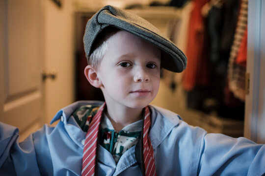 Portrait of boy wearing shirt and tie with cap while standing at home