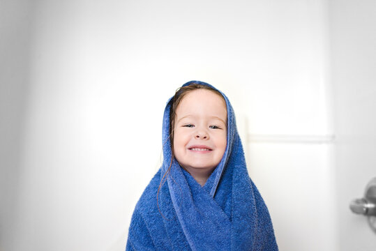 Close-up portrait of girl wrapped in towel standing in bathroom