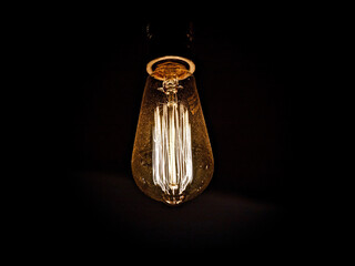 Close-up of illuminated light bulb hanging in darkroom