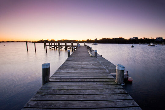 Fototapeta Wooden pier over sea against clear sky during sunrise