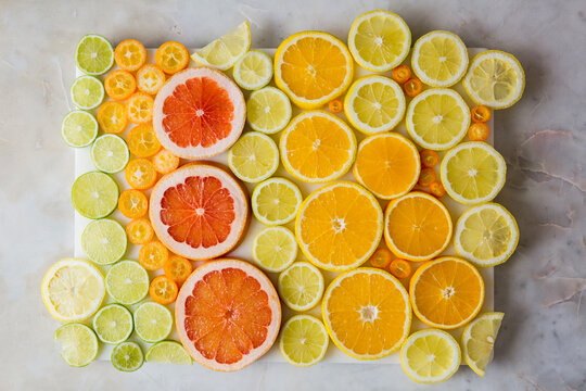 Overhead view of various citrus fruits arranged on marble table
