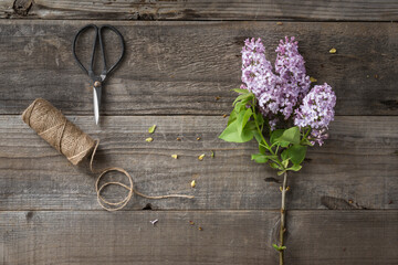 Overhead view of flowers with string and scissors on wooden table