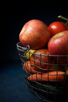 Close-up of fruits with vegetables in metal basket on table