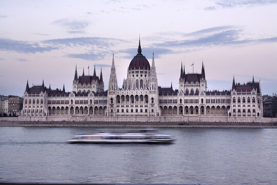 Hungarian Parliament Building by Danube River against sky during sunset