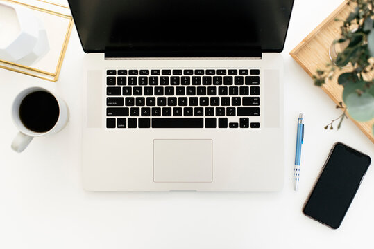 High Angle View Of Laptop Computer With Smart Phone And Black Coffee On White Desk In Office