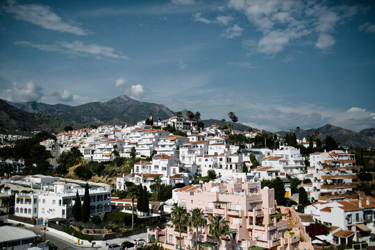 Houses in city against mountains and cloudy sky