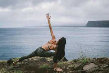 Rear view of woman practicing yoga at beach against cloudscape