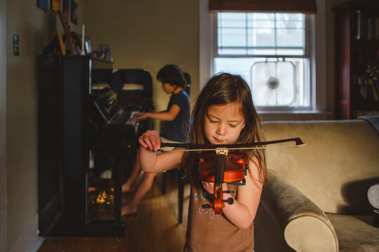 Siblings practicing musical instruments at home