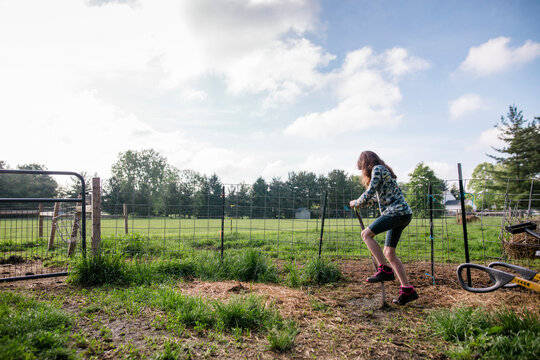 Full Length Of Girl Using Pitchfork While Digging Soil On Field