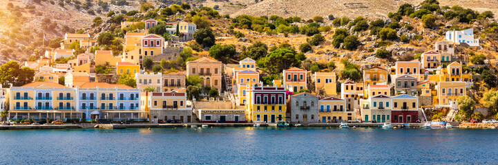 Obraz premium View of the beautiful greek island of Symi (Simi) with colourful houses and small boats. Greece, Symi island, view of the town of Symi (near Rhodes), Dodecanese.