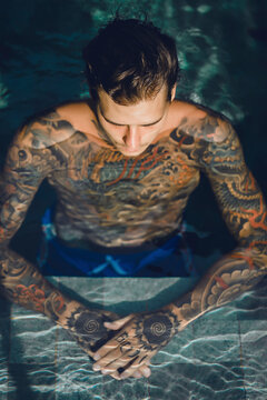 High angle view of shirtless tattooed man in swimming pool