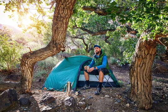 Full length of man sitting by tent in forest