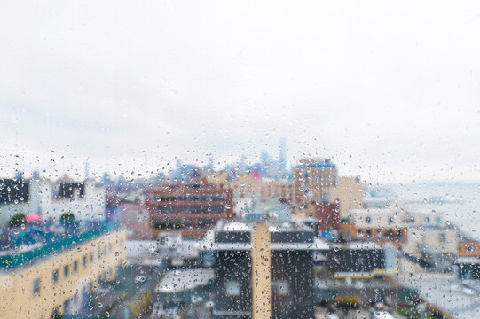 Fototapeta Buildings in city seen through wet glass window during rainy season