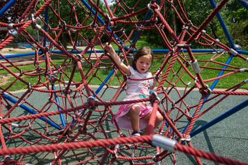 Full length of girl trapped in climbing rope net at playground