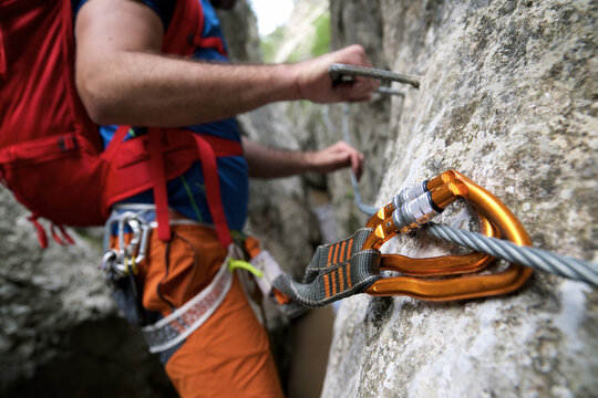 Midsection of hiker with backpack climbing on rock formation