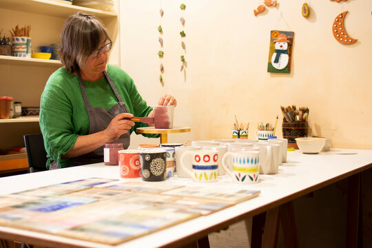 Artisan painting earthenware on workbench at pottery workshop