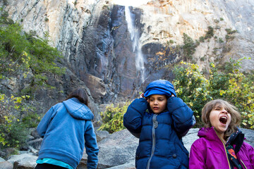 Girl screaming while siblings standing against mountains in forest at Yosemite National Park