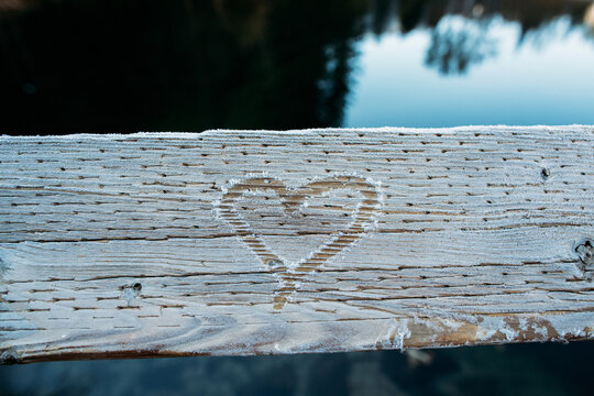 Close-up of heart shape drawn on frozen wooden fence by lake in forest at Yosemite National Park