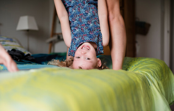 Portrait of cute playful daughter playing with mother on bed at home