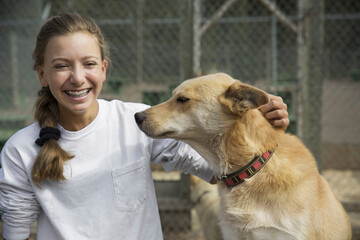 Happy teenage girl with dog sitting against fence at Banff National Park