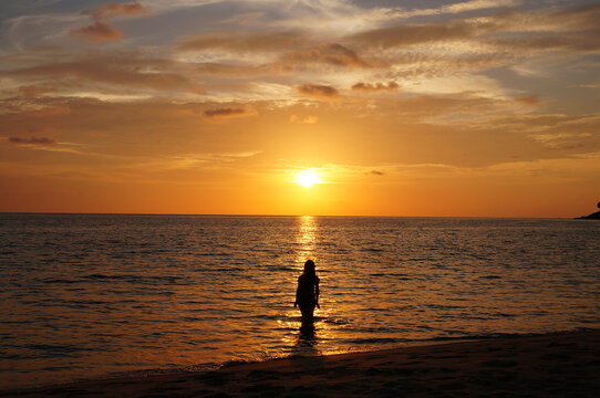 Rear view of silhouette woman standing in sea against sky during sunset