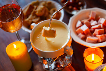 Cheese fondue with bread and snacks on a wooden table