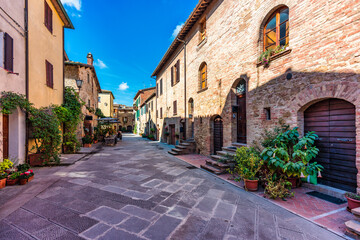 Fototapeta premium Cozy street decorated with colorful flowers, Pienza, Tuscany, Italy, Europe. Narrow street in the charming town of Pienza in Tuscany. Beautiful streets of the small and historic village Pienza, Italy