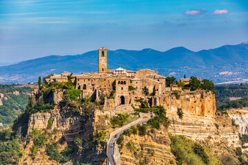The famous Civita di Bagnoregio on a sunny day. Province of Viterbo, Lazio, Italy. Medieval town on the mountain, Civita di Bagnoregio, popular touristic stop at Tuscany, Italy. - obrazy, fototapety, plakaty
