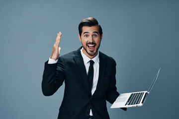 Man business looking at laptop and working online smiling with teeth surprised hand up via internet in business suit video call business talks win on blue background copy place