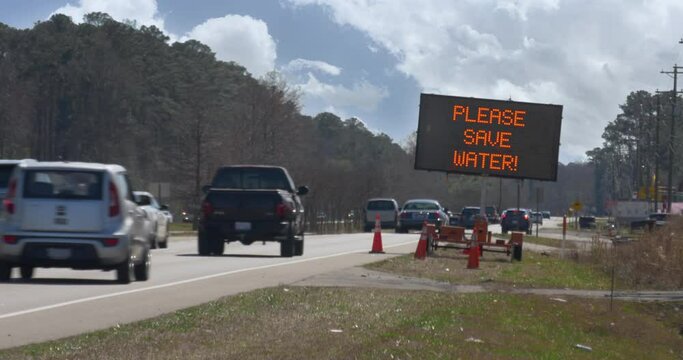 A blinking LED road sign warns passing cars of a serious drought and to conserve water.	