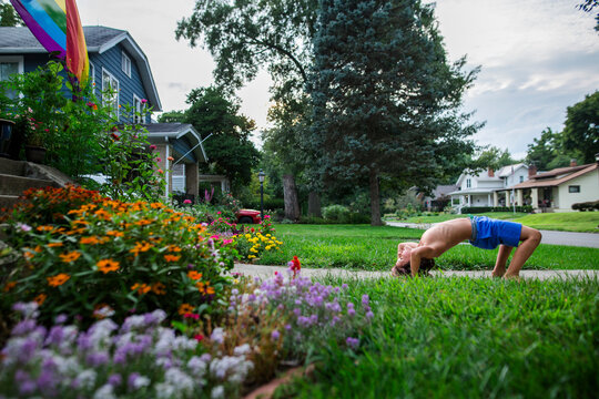 Side view of shirtless boy bending over backwards on driveway