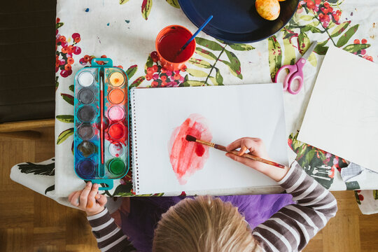 High angle view of girl painting Easter egg on table at home