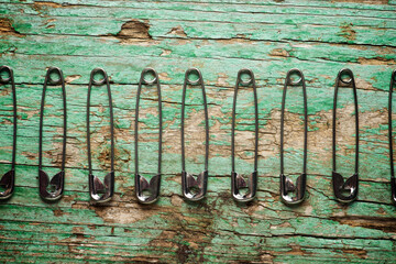 Overhead view of safety pins arranged on old wooden table