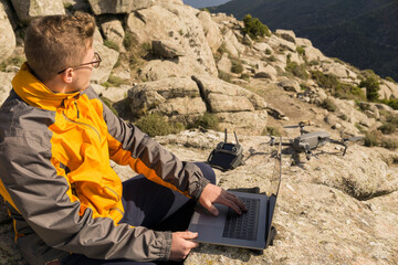 High angle view of man using laptop computer while sitting on rocky mountain