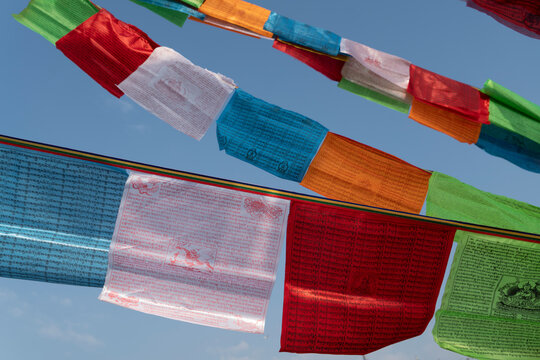 Low angle view of colorful prayer flags hanging against clear blue sky during sunny day