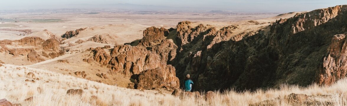 Woman sitting on rock overlooking the valley