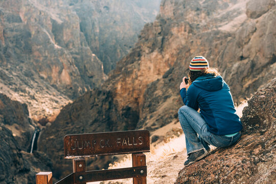 Woman taking a picture of a waterfall in the distance