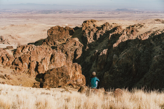 Woman sitting on a rock overlooking a canyon and valley.