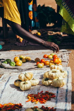 Cropped hand of market vendor arranging vegetables on fabrics for sale in market during sunny day