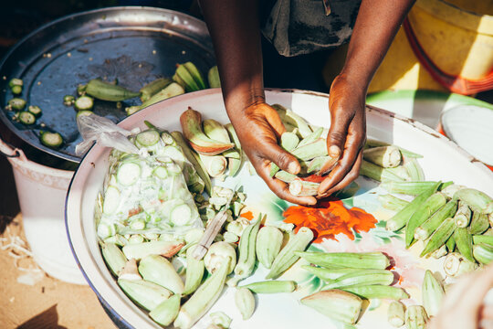 Cropped hands of vendor arranging okras in plate at market
