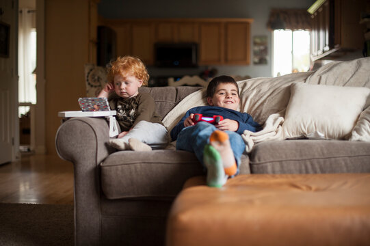 Brothers sitting on couch playing their electronics