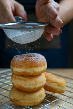 sifting icing sugar on the donuts