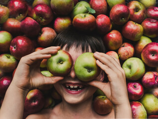Close-up overhead view of cheerful boy lying on fresh organic apples