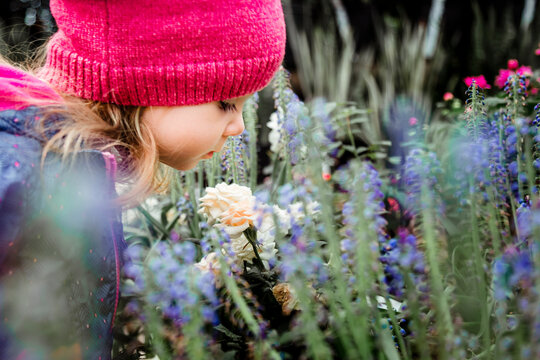 Young Toddler Girl Smelling Flowers At A Garden Center