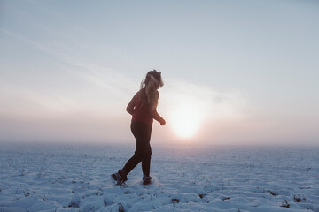 girl walks in the winter on a snowy field in a red sweater