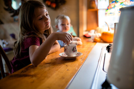 Young Girl And Sister Enjoying Hot Tea In Fancy Teacup