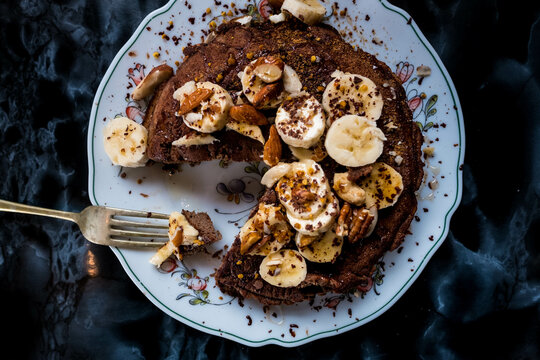 A forkful of cacao pancakes covered in banana, nuts and honey