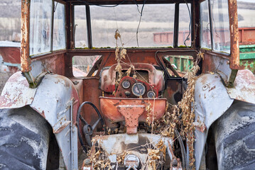 Old red rusty tractor in a field