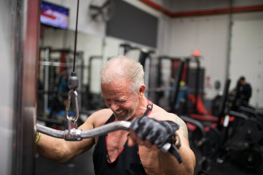 Elderly man training biceps at the gym.