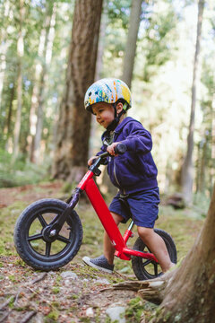 Side view of toddler boy biking in the forest